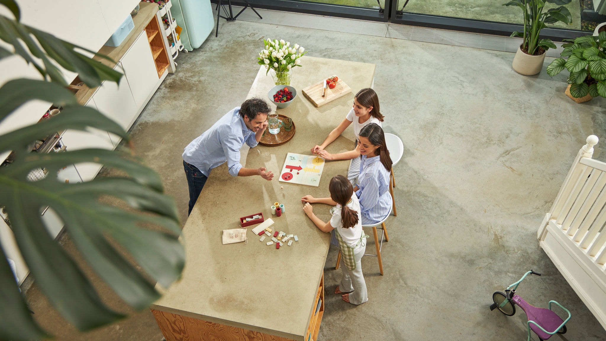 Gezin van vier speelt spelletjes rond hun keukentafel bij een perfecte temperatuur