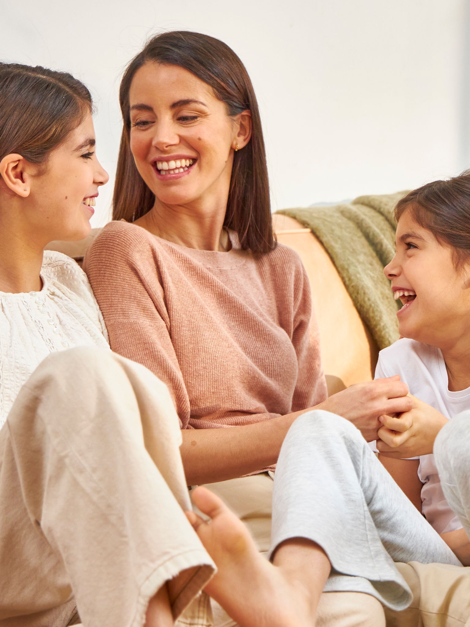Moeder en twee dochters lachen terwijl ze op de bank zitten