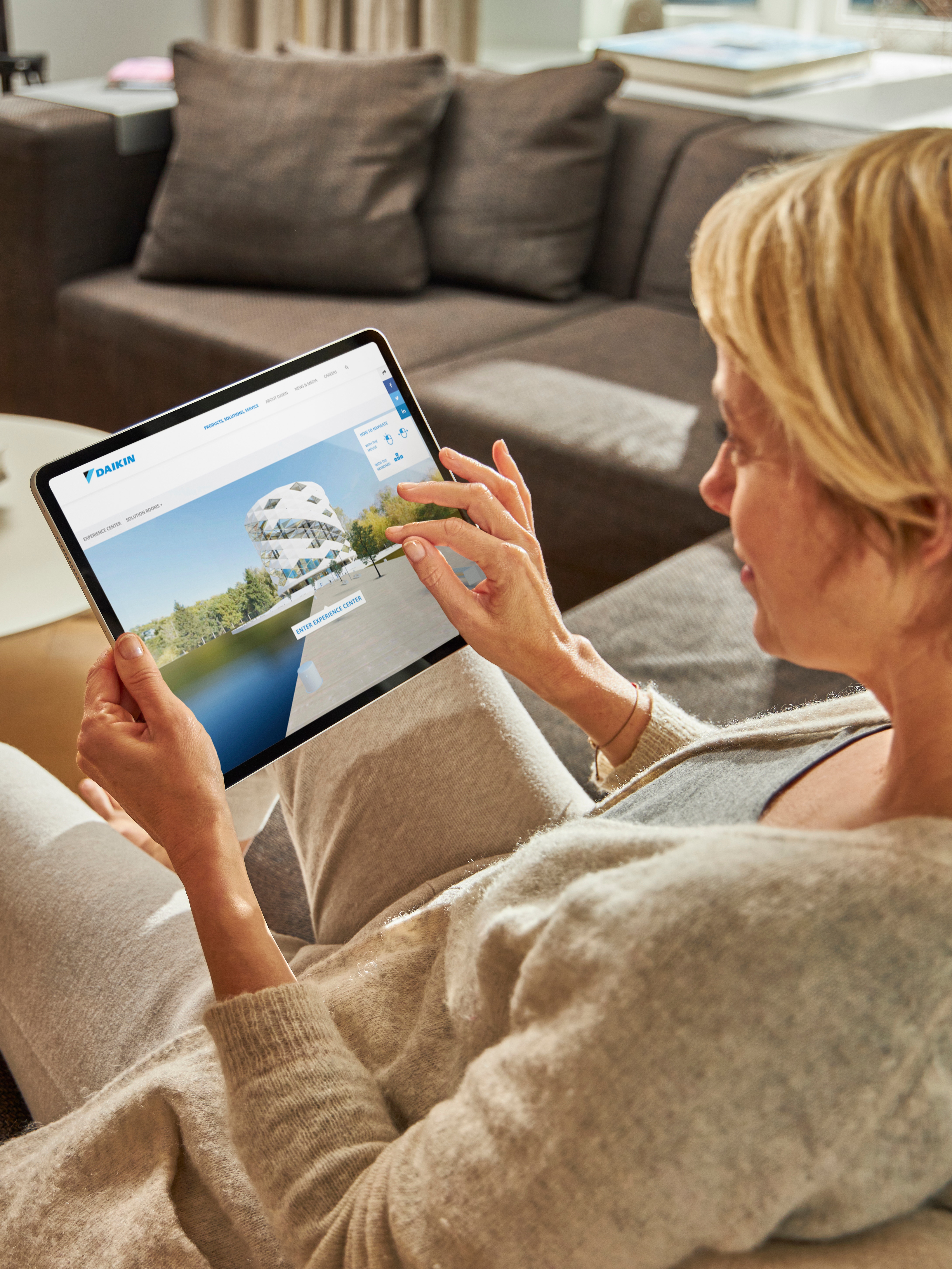 Vrouw bezoekt de Virtuele Showroom op haar tablet terwijl ze ontspant op de bank