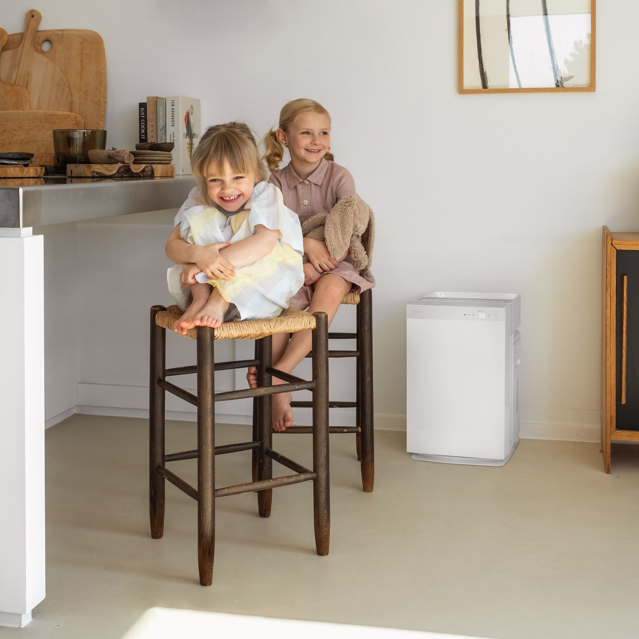 Twee jonge zussen zitten lachend op keukenstoelen