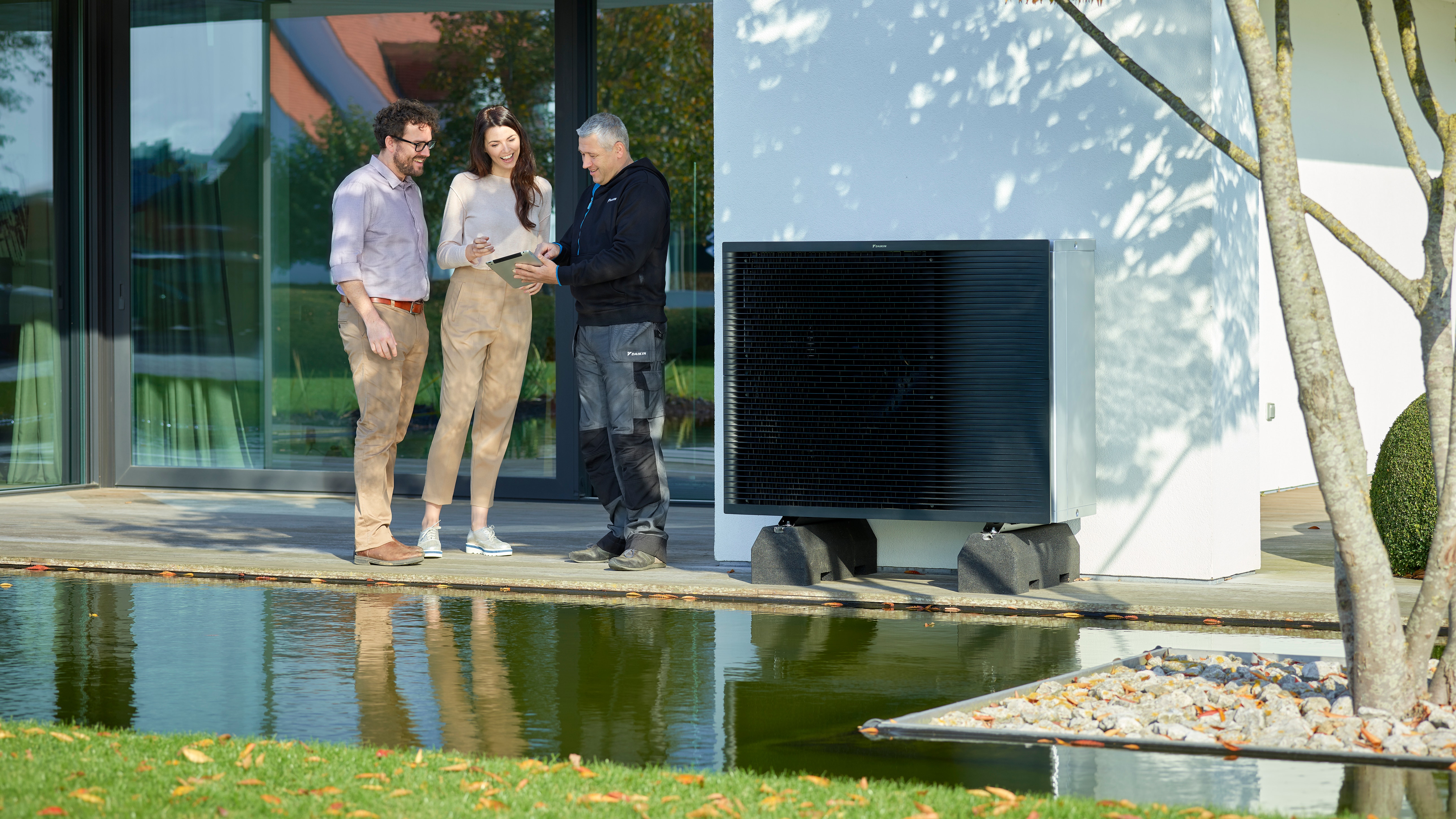 Een stel in gesprek met een installateur in hun tuin naast een Daikin Altherma buitendeel