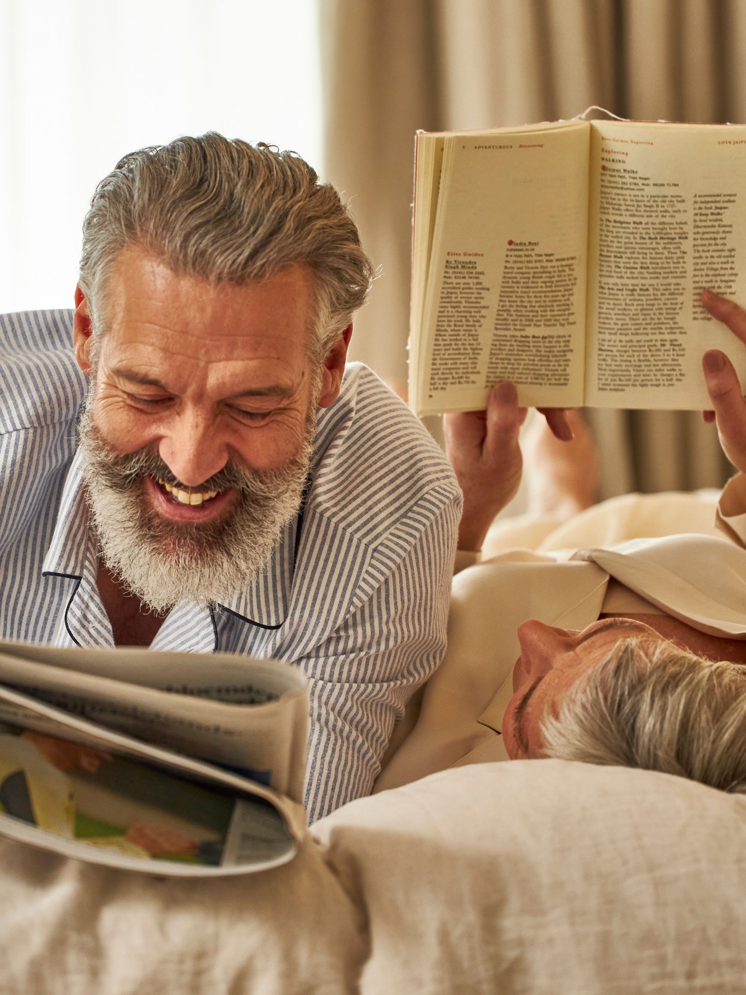 Stel van middelbare leeftijd ligt ontspannen te lezen in een slaapkamer met een goede binnenluchtkwaliteit